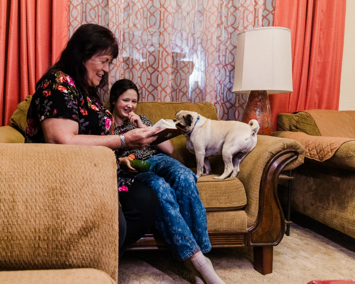  mother/grandmother and child reading on the couch with a dog